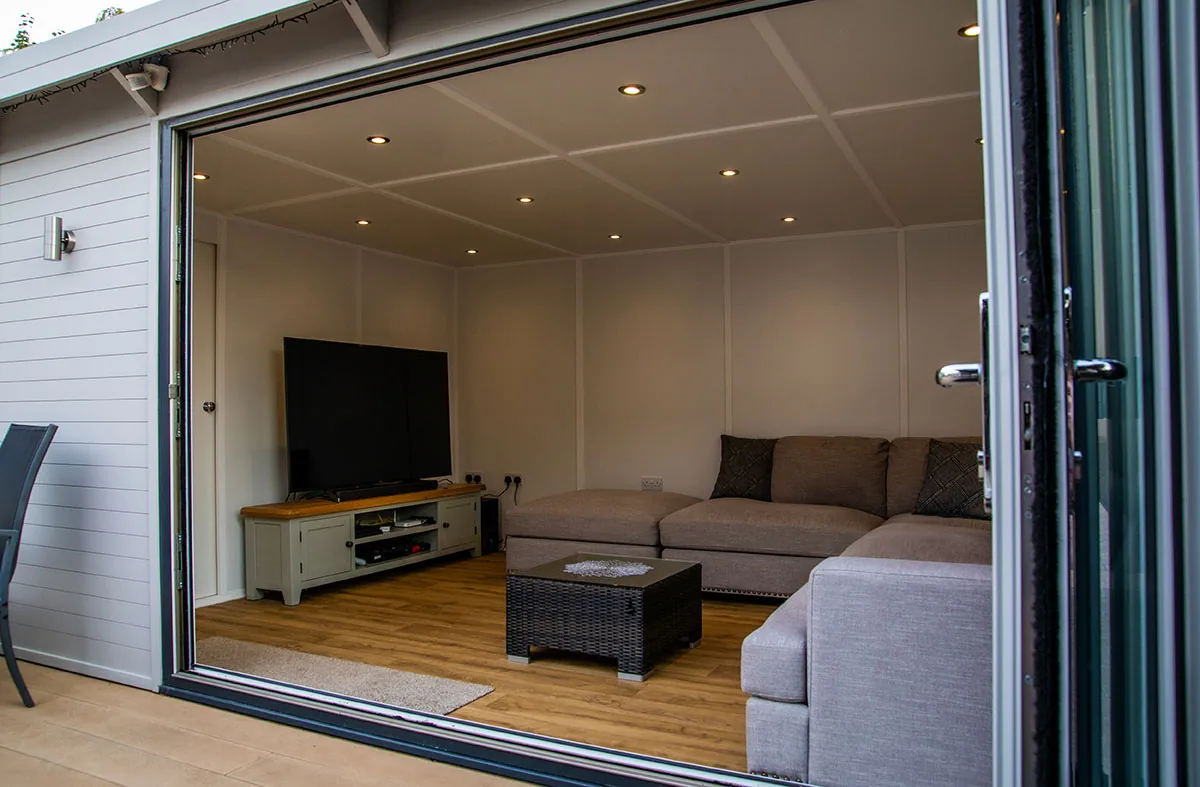 Garden room interior set up as a lounge, with a sofa, a rug and a wall-mounted television