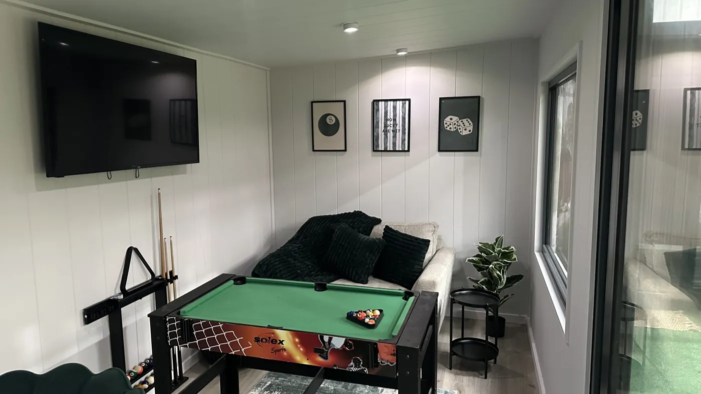 Games room display with a pool table and wall-mounted television in the Noah showroom