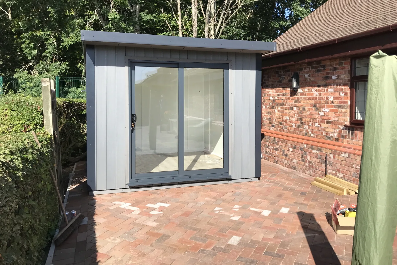 Stone grey composite Noah garden room with large sliding glazed doors onto a brick patio