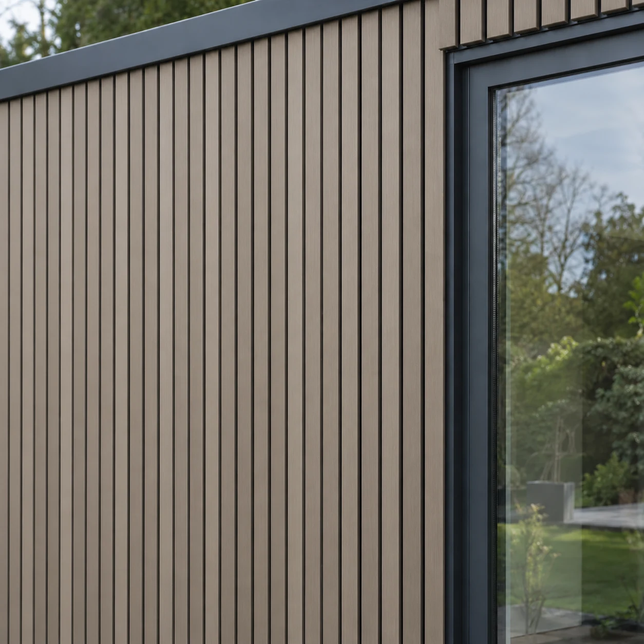 Uniform taupe slatted composite cladding beside a charcoal window frame